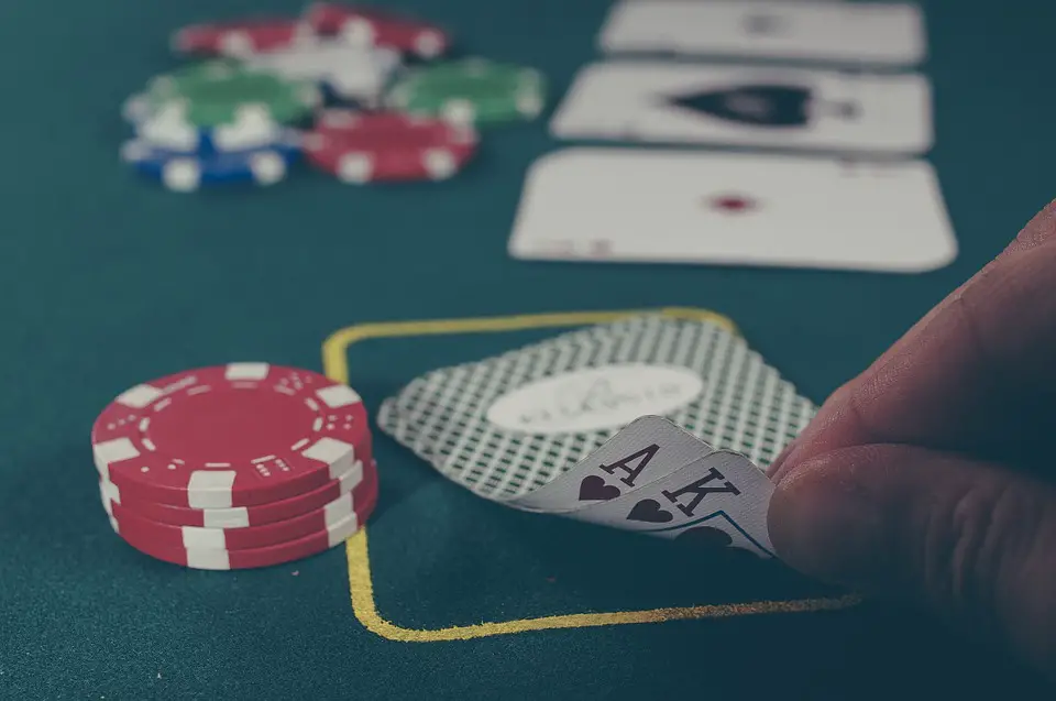 Man Secretly Viewing His Cards on a Casino Table Revealing Black Ace and King of Hearts with some chips for a Blackjack Card Game