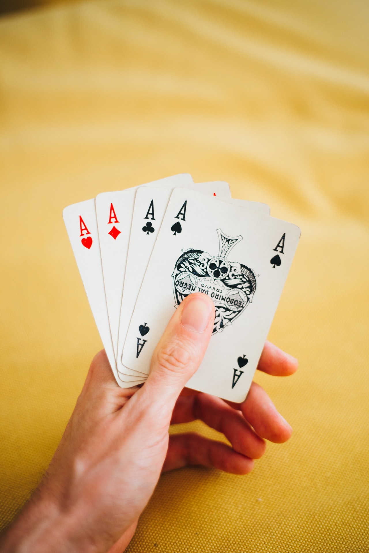 person holding four kinds of ace cards